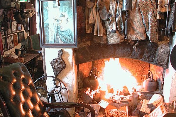 Traditional stone fireplace at Johnnie Fox’s with hanging garments, kettles and rustic décor.