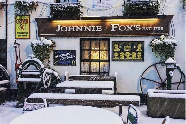 Johnnie Fox’s pub covered in fresh snow with outdoor seating and vintage décor