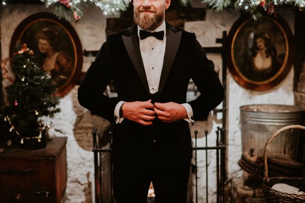 Groom adjusting his tuxedo jacket in a festive room at Johnnie Fox’s