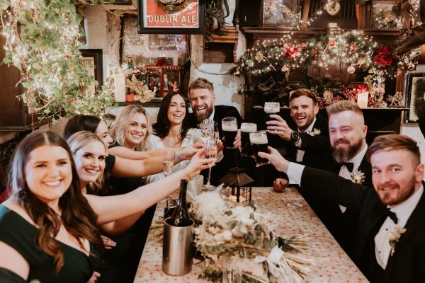 Wedding party raising glasses in a celebratory toast inside the rustic Johnnie Fox’s Pub.