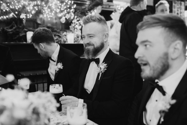 Groom and groomsmen enjoying drinks and laughing during a wedding reception at Johnnie Fox’s Pub.