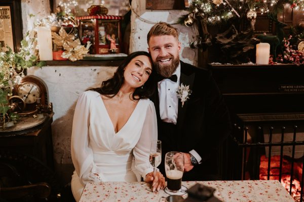 Bride leaning affectionately on the groom while they sit inside Johnnie Fox’s Pub during their wedding celebration.