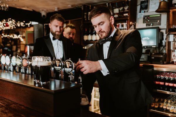 Best man pulling a pint of Guinness behind the bar during a wedding at Johnnie Fox’s