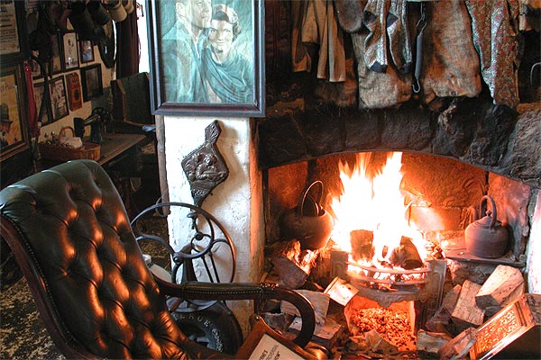 Traditional open stone fireplace with vintage décor and leather armchair at Johnnie Fox’s Pub.