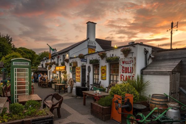Johnnie Fox’s pub exterior at sunset with outdoor seating, vintage signs, and décor