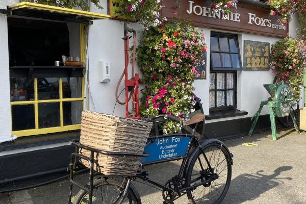 Vintage delivery bicycle with a flower-filled basket outside Johnnie Fox’s pub