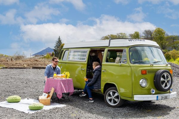 Green VW camper van with people enjoying an outdoor picnic near Johnnie Fox’s