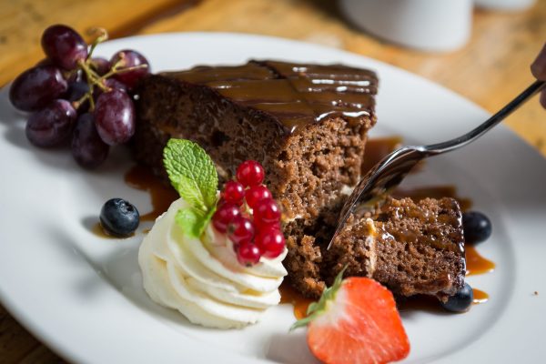 Chocolate cake with caramel sauce, whipped cream, berries, and mint