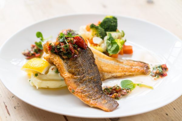Pan-seared fish with mashed potato, vegetables, and tomato salsa
