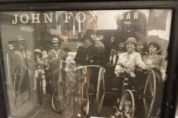 Vintage photo of the Frocken Festival at Johnnie Fox’s Pub, featuring women on bicycles and townspeople gathered.