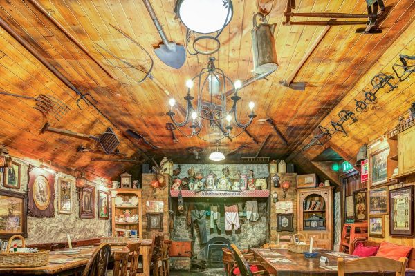 Pig House dining room with stone walls, farm tools, vintage décor and wooden tables at Johnnie Fox’s.