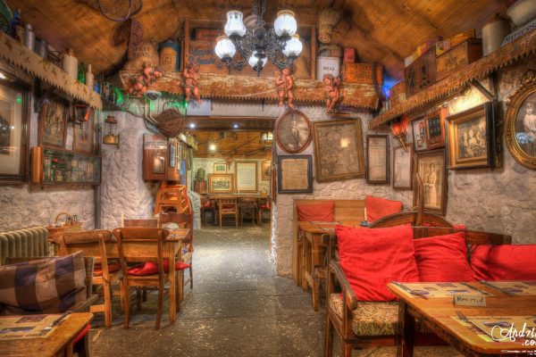 Rustic dining room at Johnnie Fox’s with wooden tables, red cushions and vintage décor on the walls.